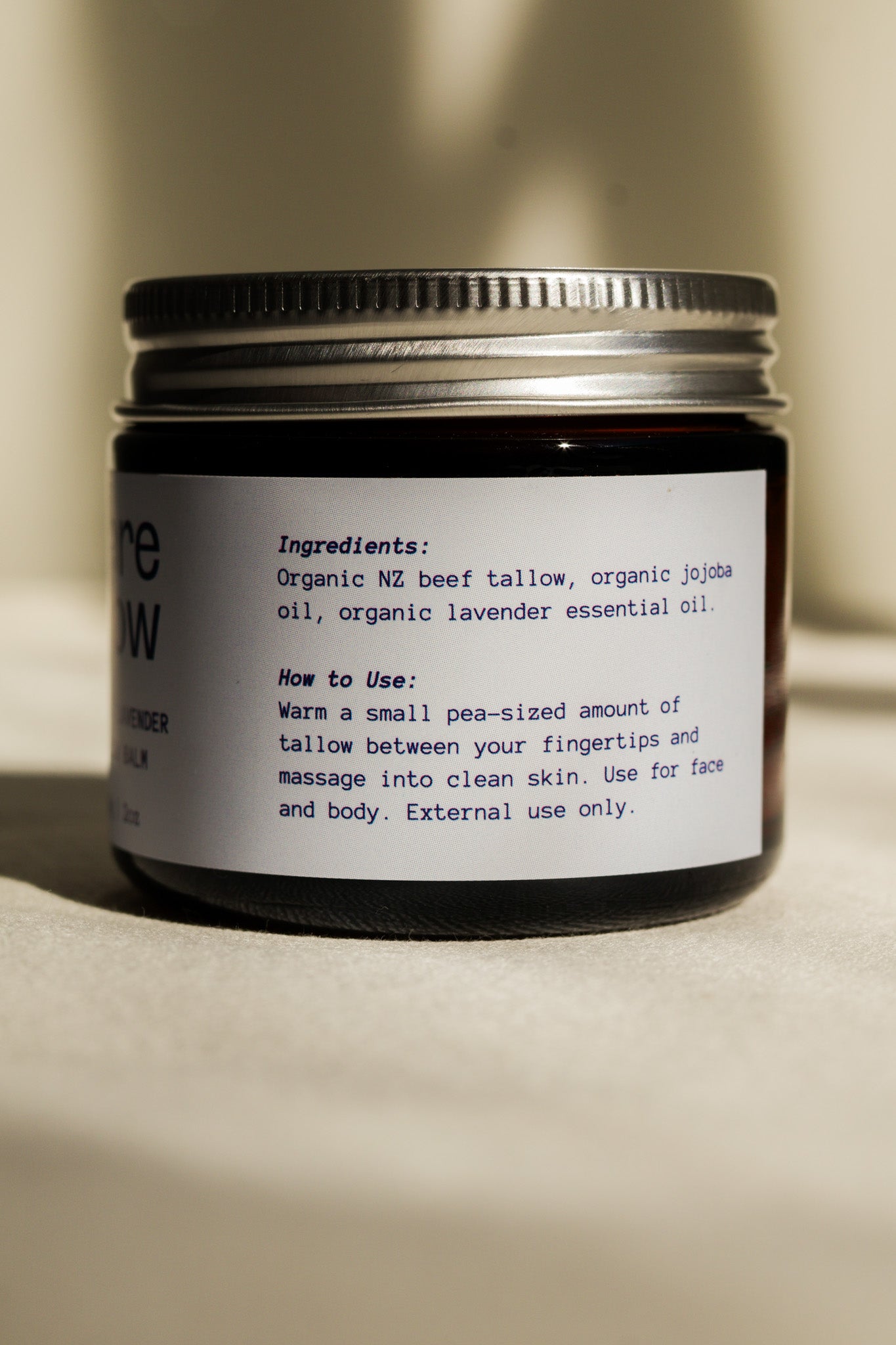 Jar of Bare Glow Organic Lavender Tallow Balm with Ingredients label on a beige background