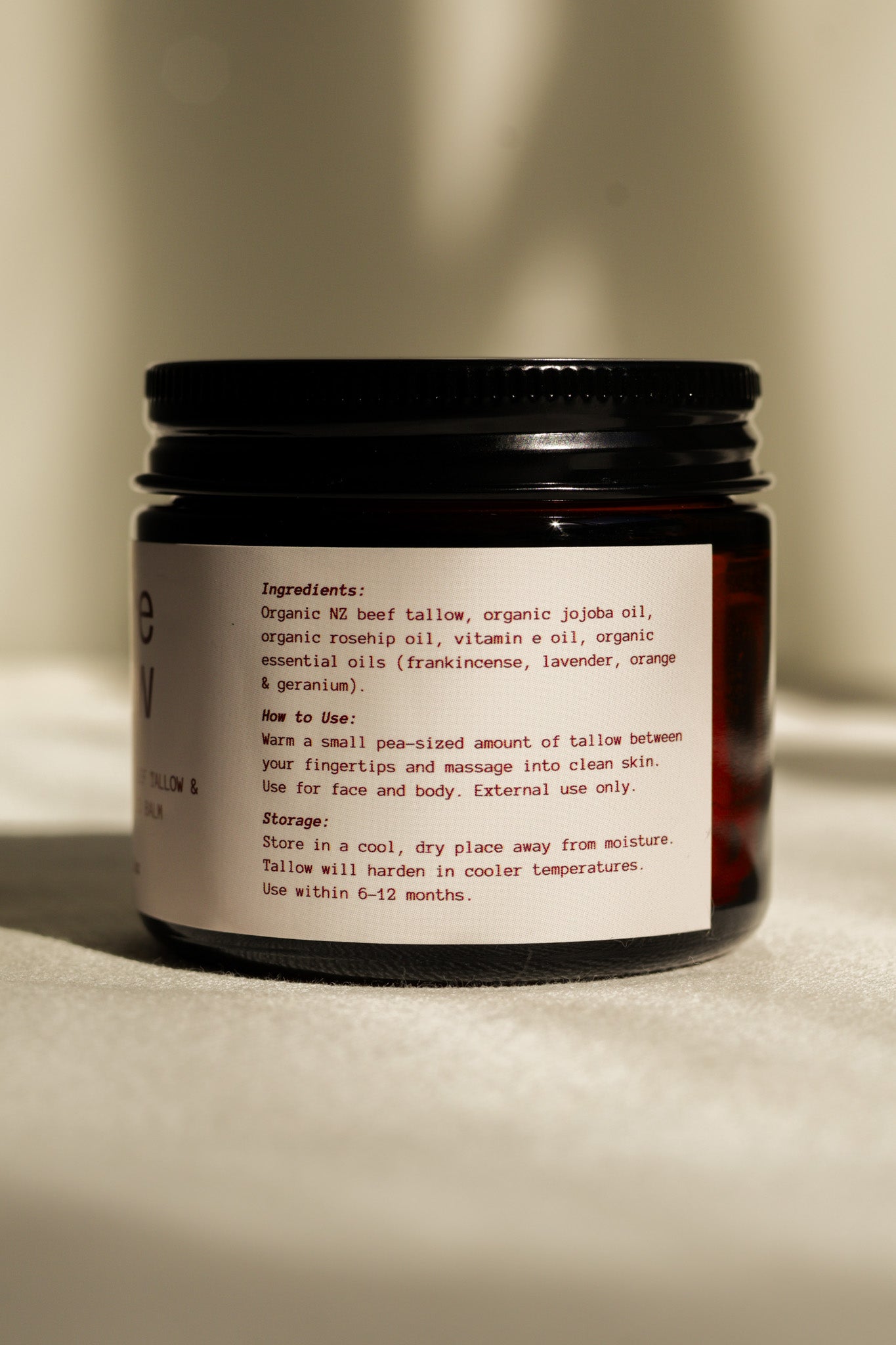 Jar of Bare Glow Organic Rosehip Tallow Balm with ingredients on display
